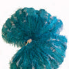 Un par de abanicos de plumas de avestruz de 3 capas de madera verde azulado y beige con una bolsa de viaje de cuero.